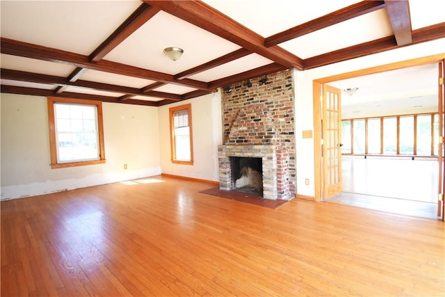 unfurnished living room with a fireplace, light hardwood / wood-style flooring, plenty of natural light, and beamed ceiling