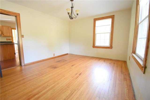 empty room featuring a chandelier and light wood-type flooring