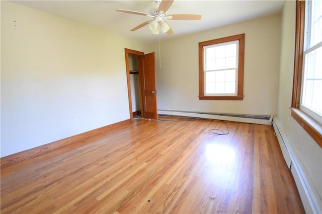 spare room with baseboard heating, ceiling fan, and light wood-type flooring