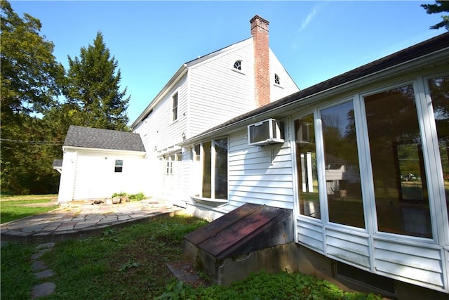 back of property featuring an AC wall unit and an outdoor structure