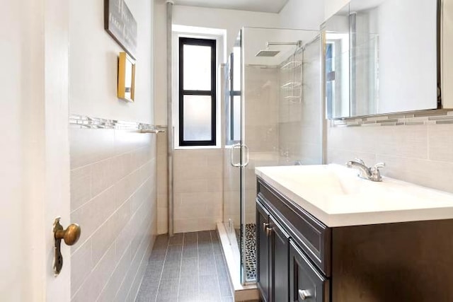 bathroom with a healthy amount of sunlight, vanity, an enclosed shower, and tile walls