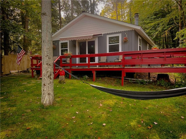 rear view of house featuring a lawn and a wooden deck