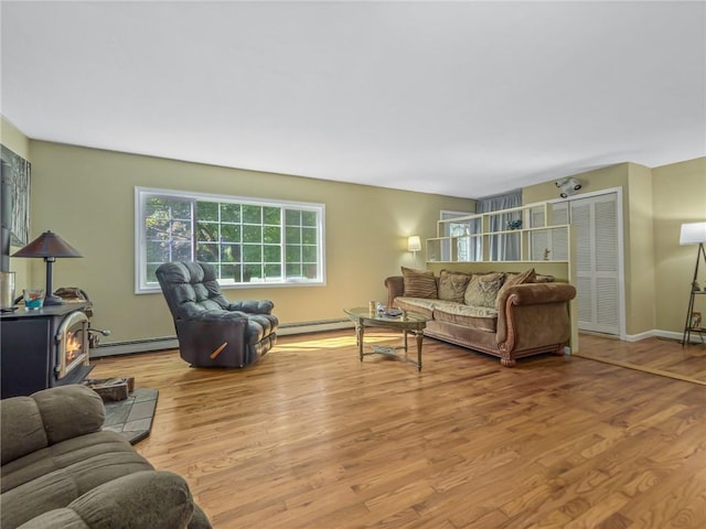 living room with light wood-type flooring, a wood stove, and a baseboard radiator