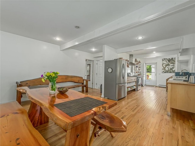 dining area with beam ceiling, light wood-type flooring, and sink