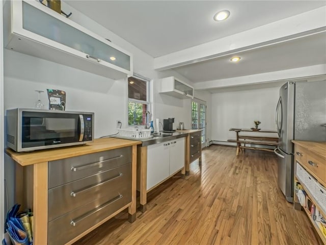 kitchen with butcher block countertops, white cabinets, stainless steel appliances, and light hardwood / wood-style floors