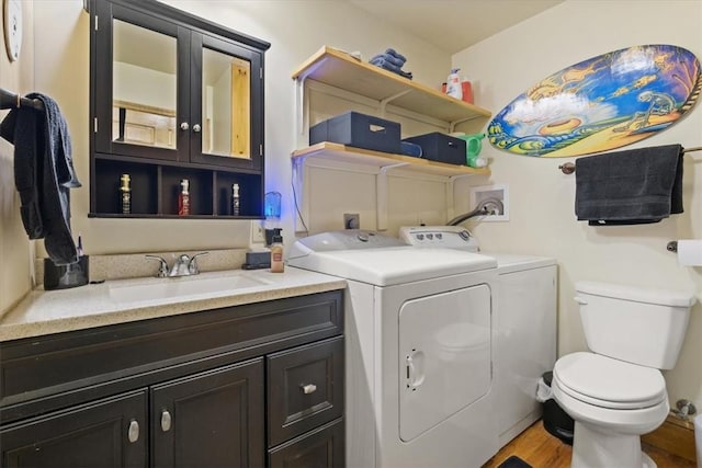 laundry room with laundry area, wood finished floors, a sink, and independent washer and dryer