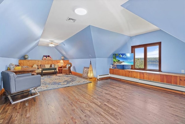 additional living space with a baseboard heating unit, visible vents, vaulted ceiling, and wood finished floors