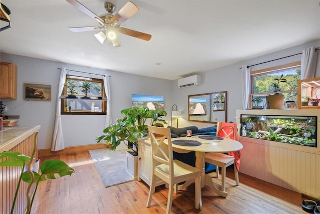 dining space with an AC wall unit, light wood finished floors, and a ceiling fan