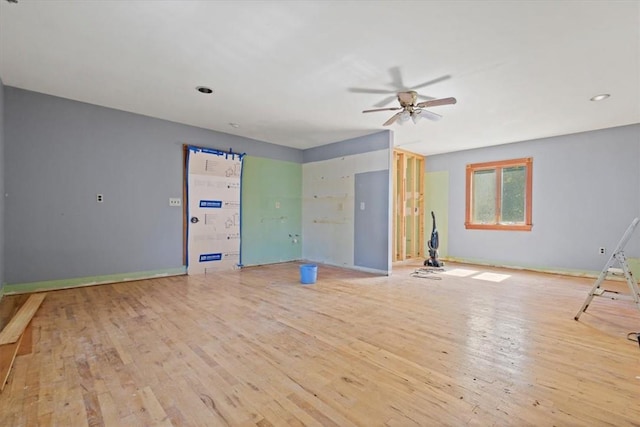 unfurnished living room featuring ceiling fan, light wood-style flooring, and baseboards