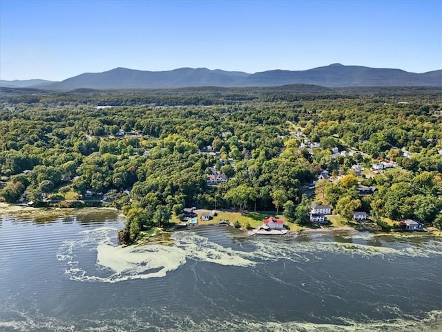 drone / aerial view with a water and mountain view and a wooded view