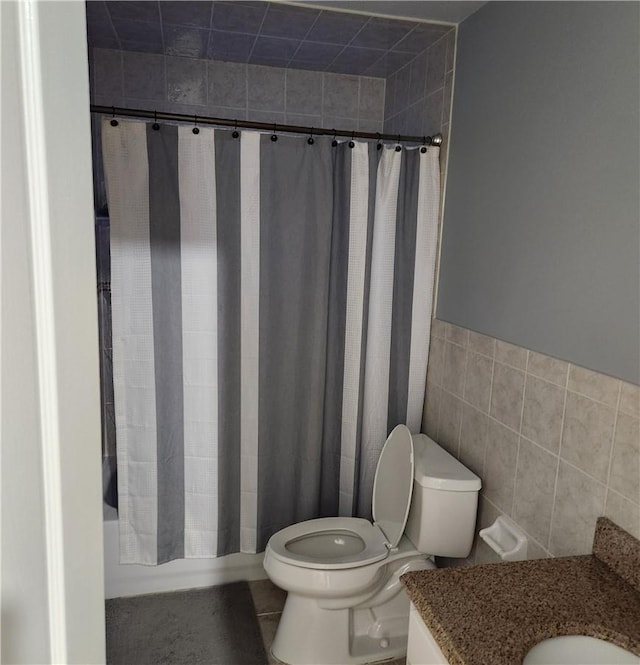 full bathroom with vanity, shower / bath combination with curtain, toilet, and tile walls