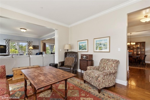 living room with hardwood / wood-style flooring, crown molding, and an inviting chandelier