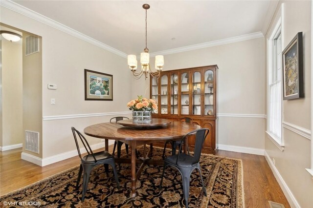 dining area featuring crown molding, hardwood / wood-style floors, and an inviting chandelier