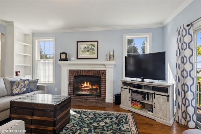 living room with built in features, dark hardwood / wood-style flooring, a brick fireplace, and crown molding