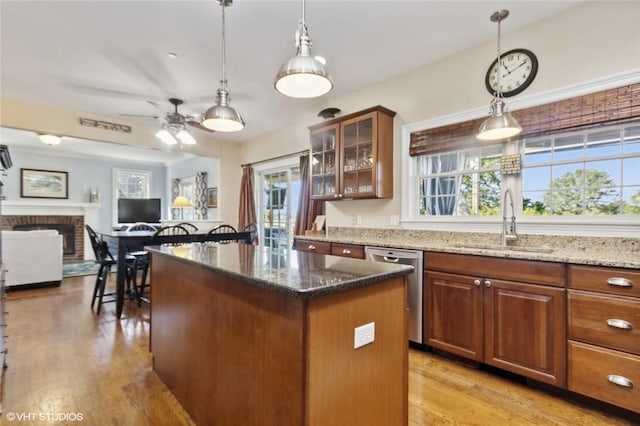 kitchen with sink, stainless steel dishwasher, dark stone counters, light hardwood / wood-style floors, and a kitchen island