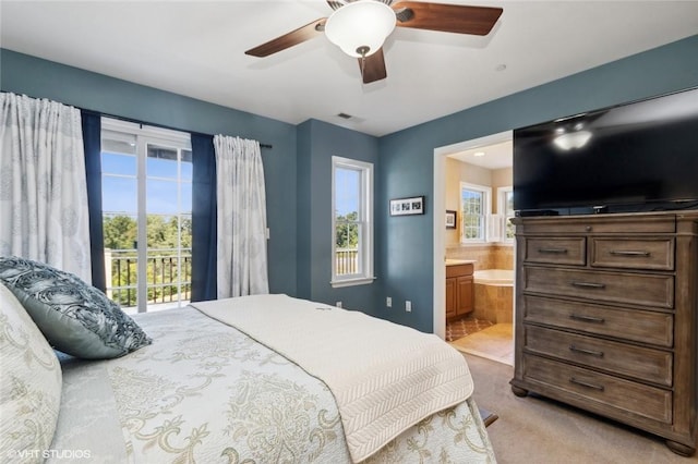 carpeted bedroom featuring access to exterior, ceiling fan, ensuite bathroom, and multiple windows