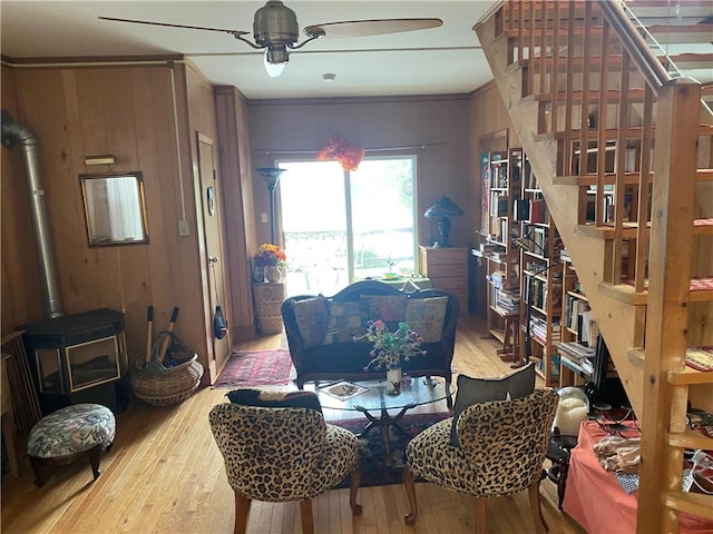 dining room featuring wooden walls, light hardwood / wood-style flooring, ceiling fan, and ornamental molding