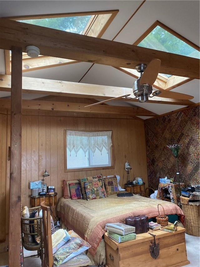 bedroom with wood walls, vaulted ceiling with skylight, and ceiling fan