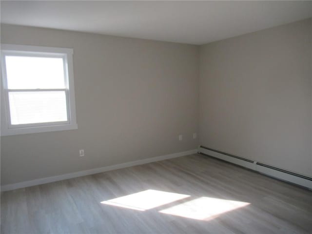 unfurnished room with light hardwood / wood-style floors and baseboard heating