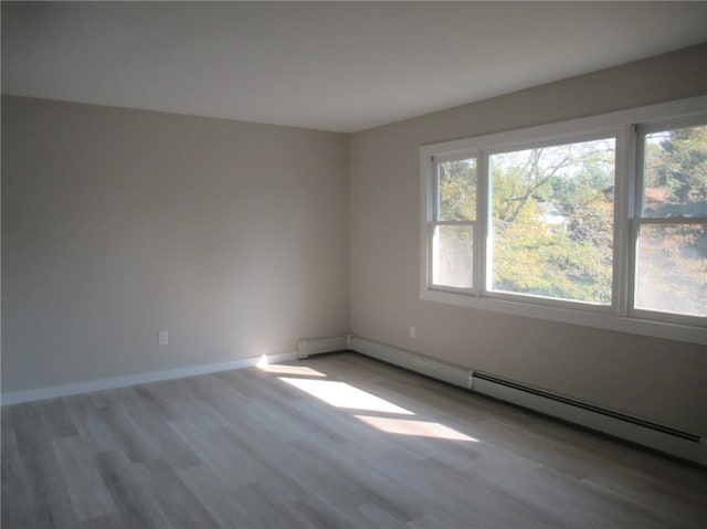 spare room with wood-type flooring, baseboard heating, and a wealth of natural light