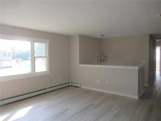 unfurnished room with a chandelier, wood-type flooring, and a baseboard heating unit