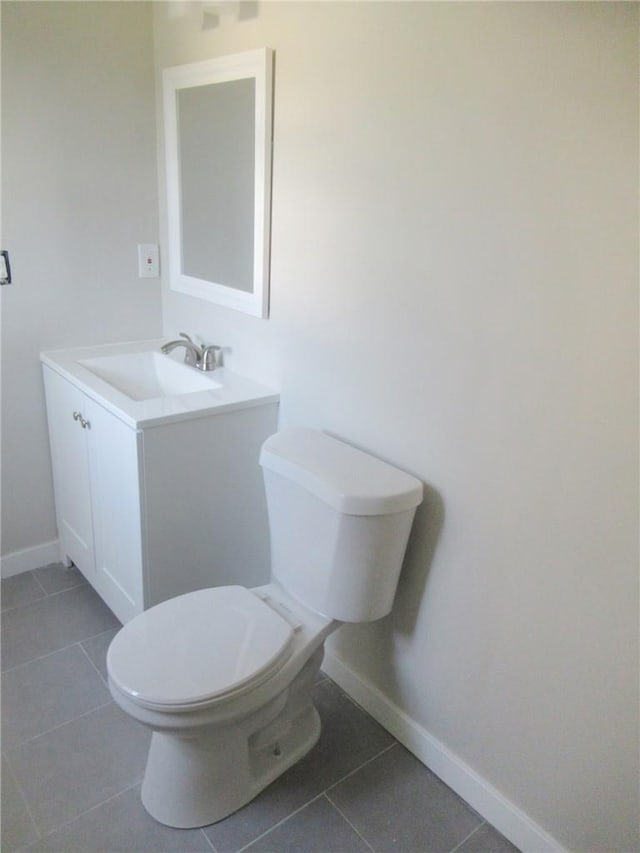 bathroom with toilet, vanity, and tile patterned floors