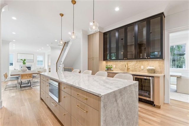 kitchen with a healthy amount of sunlight, a center island, beverage cooler, and light hardwood / wood-style flooring