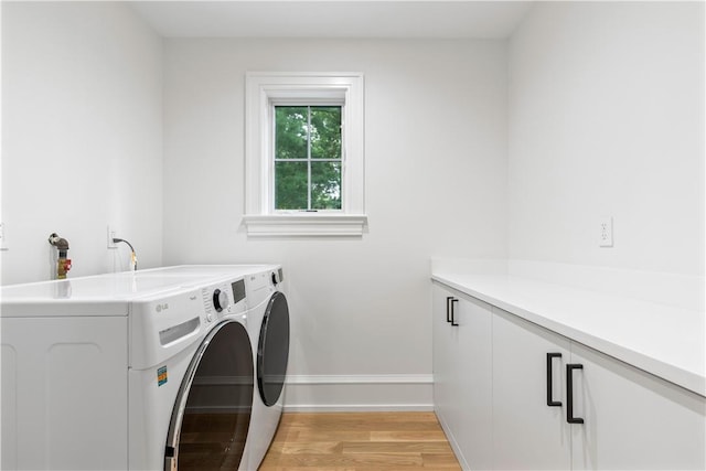 clothes washing area featuring light hardwood / wood-style floors, cabinets, and washing machine and clothes dryer