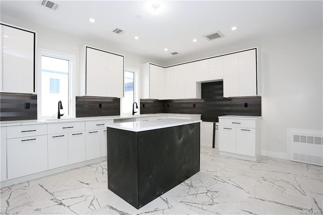 kitchen with a center island, white cabinetry, and sink