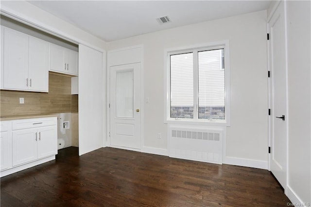 kitchen with white cabinetry, radiator heating unit, and dark hardwood / wood-style floors