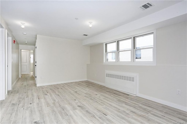 spare room featuring radiator heating unit and light wood-type flooring