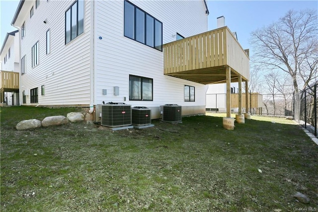 rear view of house featuring a deck, central AC unit, and a lawn