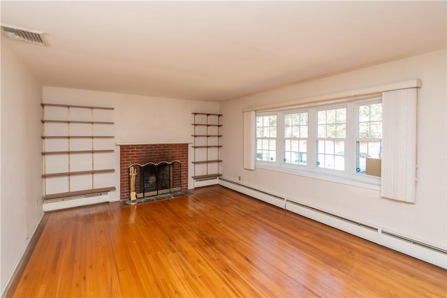 unfurnished living room with hardwood / wood-style floors, a baseboard radiator, and a brick fireplace