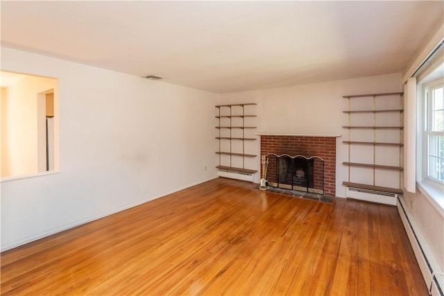 unfurnished living room featuring hardwood / wood-style flooring, a brick fireplace, and baseboard heating