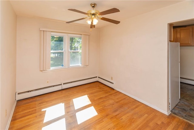 spare room featuring ceiling fan, light hardwood / wood-style floors, and baseboard heating