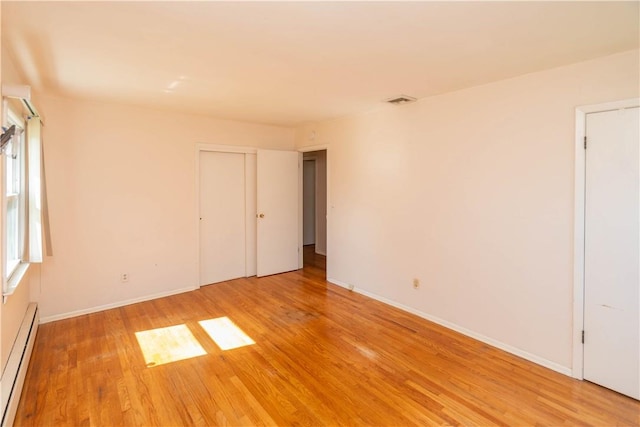 unfurnished room featuring a baseboard radiator and light wood-type flooring