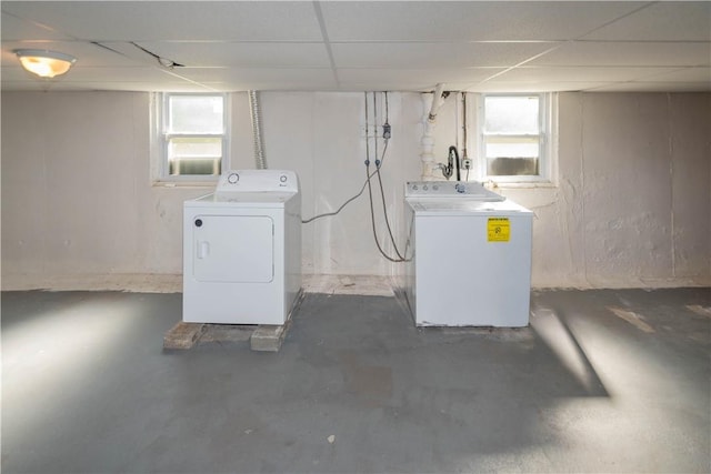 basement with a drop ceiling, washer and clothes dryer, and a healthy amount of sunlight