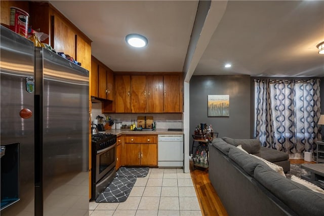 kitchen featuring black gas range, dishwasher, tasteful backsplash, stainless steel fridge, and light hardwood / wood-style floors