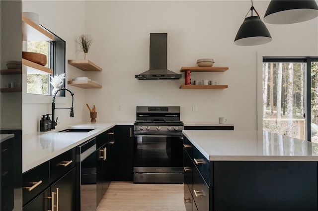 kitchen featuring a healthy amount of sunlight, hanging light fixtures, sink, range hood, and gas stove