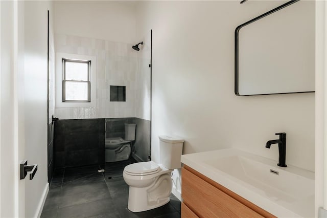 bathroom with tile patterned flooring, vanity, toilet, and tiled shower