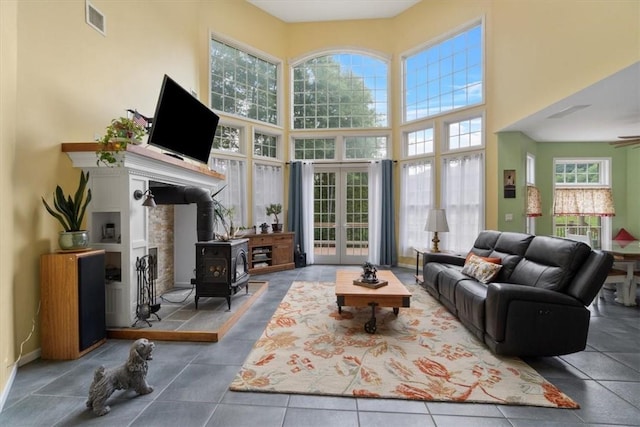 living room featuring a towering ceiling, tile patterned floors, and a wood stove