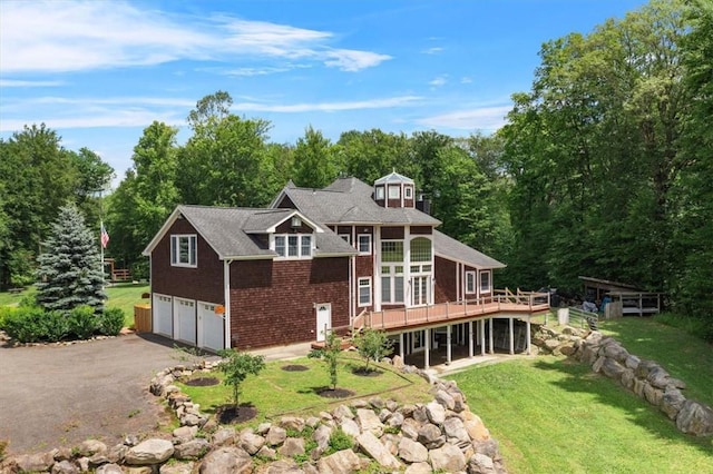 rear view of house featuring a wooden deck, a garage, and a lawn