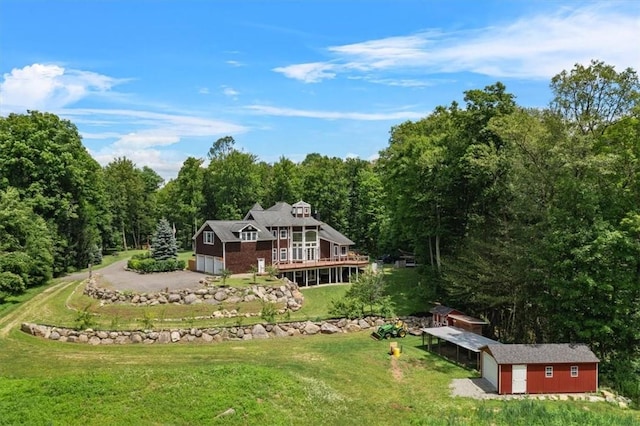 back of property featuring a garage, a yard, an outdoor structure, and a deck