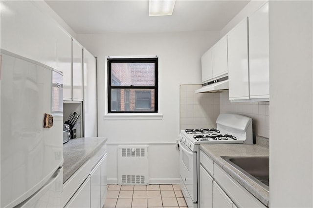 kitchen with radiator heating unit, white appliances, tasteful backsplash, and white cabinetry