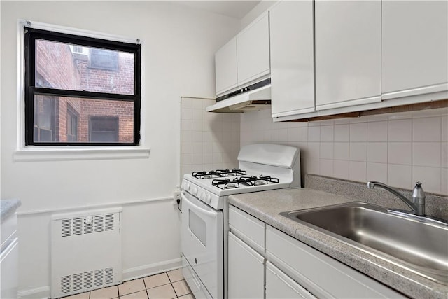 kitchen with radiator, sink, white gas range oven, decorative backsplash, and white cabinetry