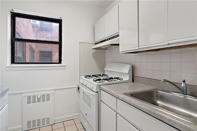 55A Ehrbar Ave Unit 2G, Mount Vernon, NY 10552 - kitchen with white range with gas stovetop, under cabinet range hood, white cabinets, radiator, and backsplash