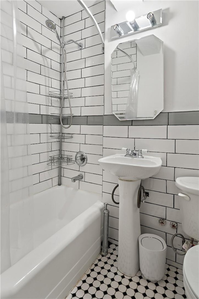 full bathroom with tiled shower / bath combo, toilet, tile walls, and sink