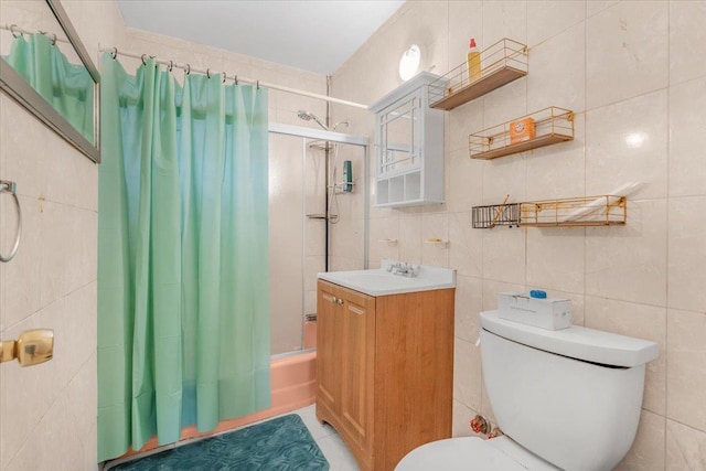 full bathroom with tile patterned flooring, toilet, shower / bath combo with shower curtain, vanity, and tile walls