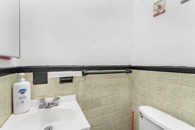 bathroom featuring vanity, tile walls, and toilet