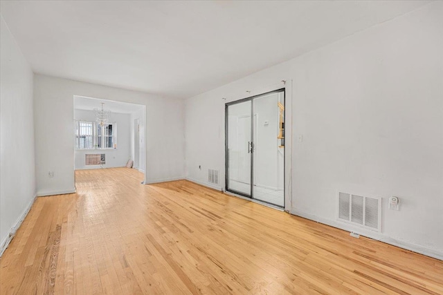 unfurnished room with light hardwood / wood-style floors and a chandelier